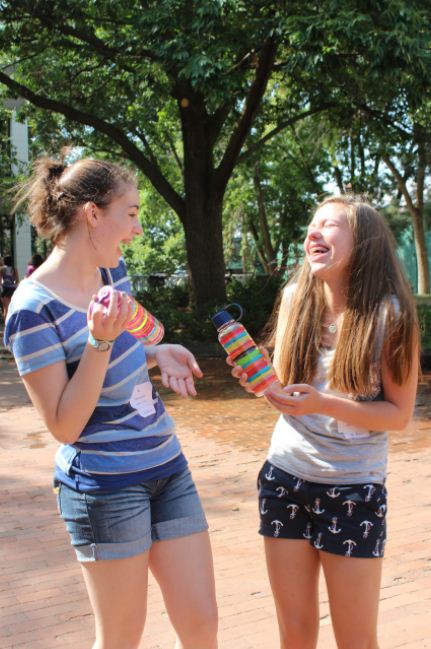 Freshmen Mary Grant and Barbara Bathke admire their new water bottles, which were given out during freshman orientation. It is way too hot, but were having fun! Grant said.