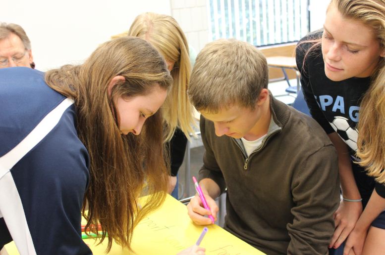 Junior Sarah Romans, senior Harrisen Egly, and junior Julia Hansen work on signs. “One sign we’re making this week says, ‘It’s finally time for our homecoming week. Take your friends keys, don’t turn the other cheek,’” Egly said.