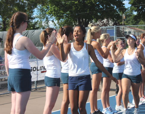 Doubles  partners senior Aria Bryan and sophomore Ella Hommeyer get high-fives from their teammates before a match against St. Anthony Village High School on  Sept. 12. “We work really well together, everybody gets along really well, and we all have really good sportsmanship which is awesome,” senior captain Alida Mitau said. 