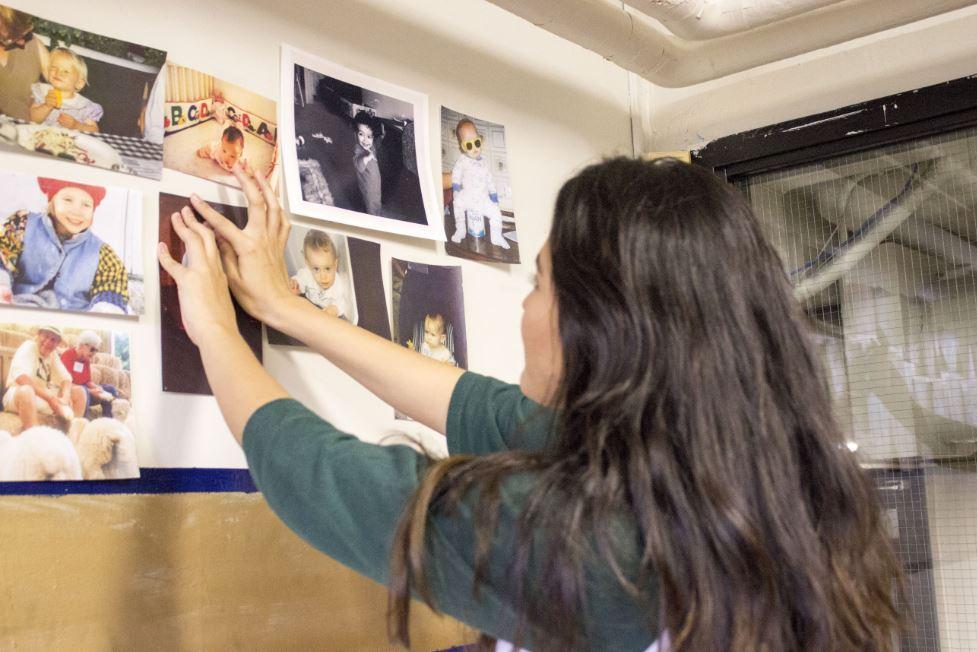 Senior Class Leadership Council member Emma Chang puts up a senior's baby picture on the wall of the senior lounge. “The reason why we have the baby pictures is to show yourself from when you are really little, and once you give your speech, it shows the change,” Chang said.