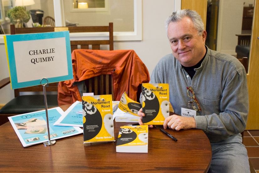 Author Charlie Quimby sits at his book signing table in the Summit Center on Nov. 20. Writing fiction is about writing things that are important for you instead of [for] your client, he said. 