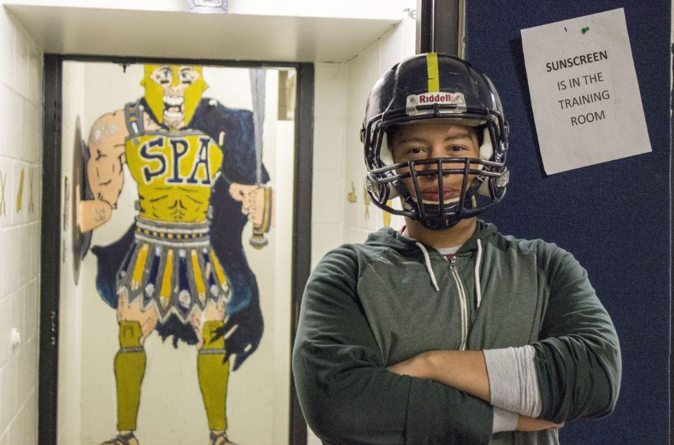 Football captain senior Sam Carlson poses in front of the boys locker room. "We turn the lights off and we all envision ourselves making good plays. It just gets us really pumped up,” junior Louie Bogolub said.