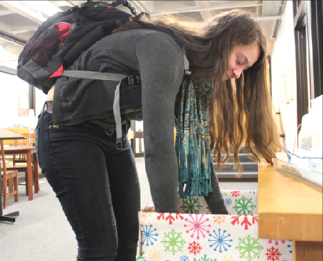 Junior Julia Lagos adds toys to the Toys for Tots drop box outside the Dean’s Office. “ [Adopt a Family] was just a lot of work to do around the holidays with so much to do already,” senior Aria Bryan said. “So we thought that Toys for Tots would be a good substitution.” 