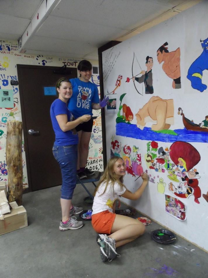 Sophomore Calla Saunders paints a mural of Disney characters with French lyrics at Concordia French Language Lac du Bois. “It helps to connect things we’re familiar with, like Disney movies, with the new language that we’re learning,” Saunders said.