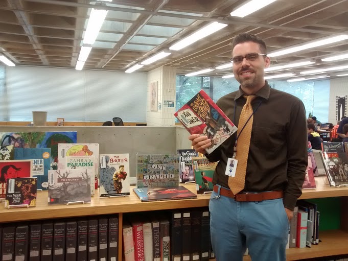 Upper School dean Max Delgado poses with the book The Contract with God Trilogy by Will Eisner. Eisner is an “incredible visual storyteller. Delgado said. 
