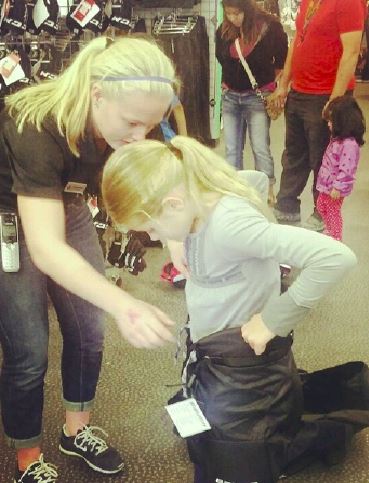 Junior Catherine Johnson helps fit a customer in hockey gear during her  shift at Total Hockey where she works helping hockey players find what they need for ice. “During the fall, all of the new products come in and they’re the most popular,” Johnson said. 