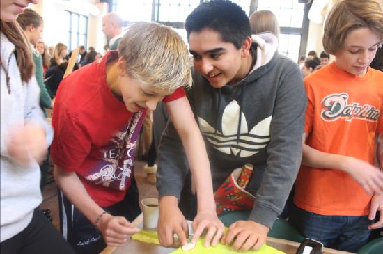 Freshmen ned Laird-Raylor and Turab Naqvi wrap presents for Adopt-a-Family with their advisory in the cafeteria on Dec. 10. The event is hosted by Community Action and Service. “We want to put a large emphasis on local action and local volunteer work and we know that these gifts are going to families that are in the Twin Cities,” CAS president Samantha Linn said.