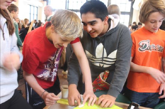 Freshmen ned Laird-Raylor and Turab Naqvi wrap presents for Adopt-a-Family with their advisory in the cafeteria on Dec. 10. The event is hosted by Community Action and Service.  “We want to put a large emphasis on local action and local volunteer work and we know that these gifts are going to families that are in the Twin Cities,” CAS president Samantha Linn said.