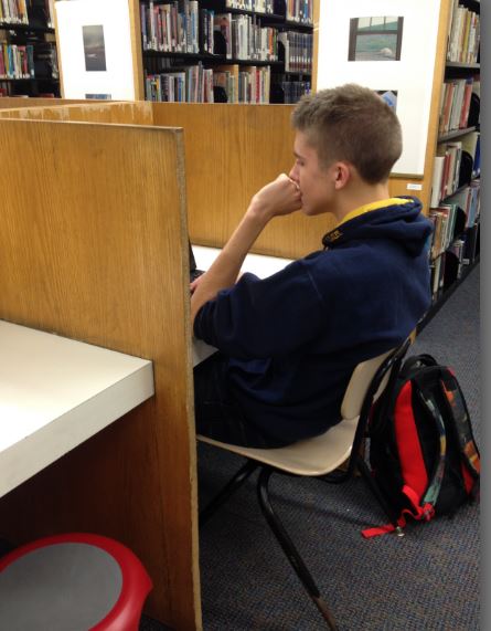 Junior Sam Matenaer takes advantage of the isolation provided by the cubby desks in the library. “It’s not a table, so I’m sitting alone, so it’s easier to focus on my work,” he said. 
