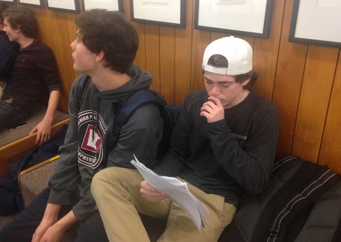 Sophomore Jack Johnston reads his teacher comments while sitting on the sophomore benches. “It helps me set goals for how to get better during the second semester,” Johnston said.