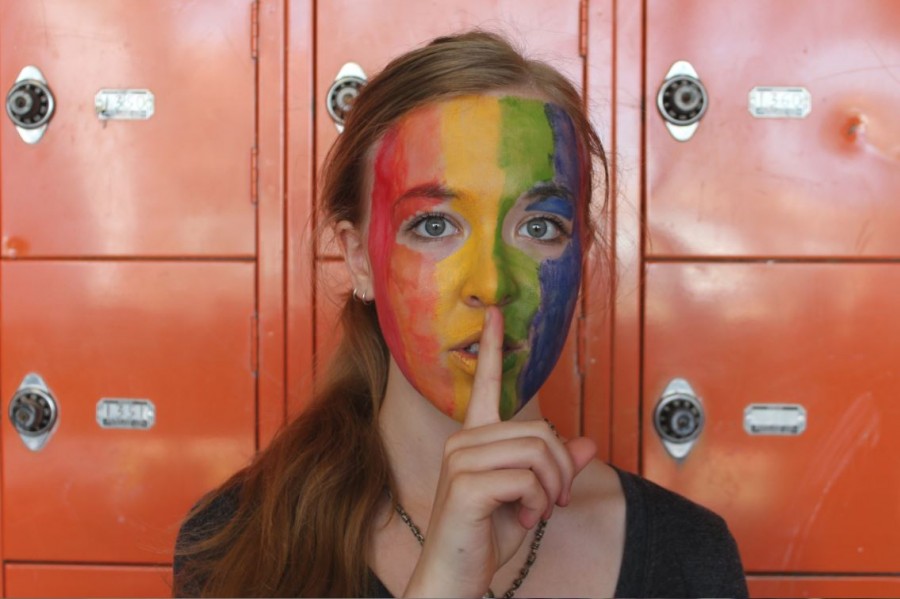 Junior Miriam Tibbetts poses for the National Day of Silence on Apr. 17 with a finger over her mouth. This action symbolizes the quiet that is used to make a bigger sound. The face paint shows support for the LGBTQ+ community. “It’s important to use Day of Silence to pay tribute to those who have been silenced, to help show people they aren’t alone in feeling silenced, and encourage change to help people regain their voices,” senior GSA Co-President Maggie Clark said.