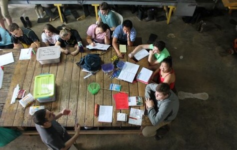 Students all gathered at a large work table for group meetings with Dr. Adrian Pinto