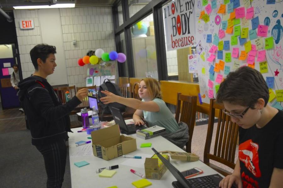 Sophomore Lauren Datta sticks a post-it-note on the HerSpace’s body mural. “There’s something about writing [what you love about your body] down, and actually committing it to paper that makes it seem a little more real,” HerSpace co-president Maggie Vlietstra said. 
