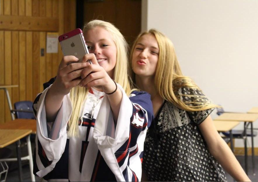 Seniors Catherine Johnson and Lexi Hilton take a selfie, keeping in mind the rules addressed in the new photo and video policy. The policy manifests itself in other aspects of Johson's school life, too. "We now have a box outside of our hockey locker room. We're not allowed to have phones inside the locker room anymore," Johnson said. 