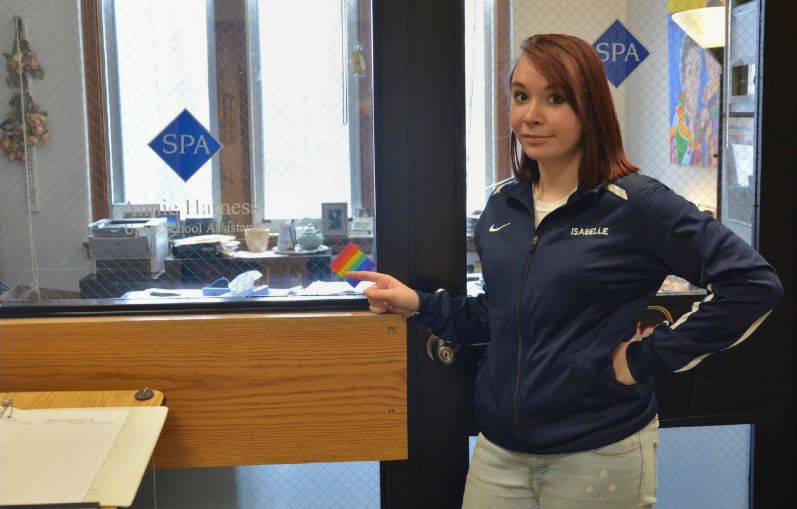 Junior Isabelle Bukovsan points to one of the old rainbow stickers given to teachers and staff to designate their offices and classrooms as safe spaces for LGBTQ+ youth. "It fell apart when people changed offices," Bukovsan said. The new signal will be a paperweight, because paperweights are "visible and also mobile," Bukovsan added. 