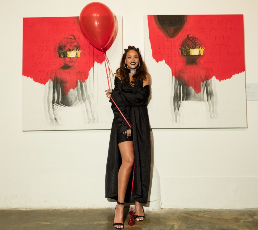 Rihanna holds up a red balloon, and poses in front of the album’s artwork, at the cover art reveal.