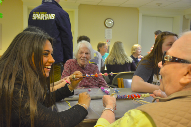 Senior Sami Brattland works with a partner at Lyngblomsten Retirement Community to make colorful clay beads. The beads will go to children with cancer or long-term illness around the country. 