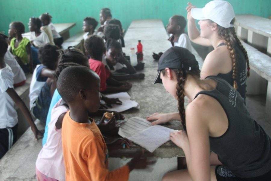 Freshman Mimi Geller and sophomore Greta Sirek sit and read with school kids through the Haitian Initiative. Unlike mission-related trips, Haitian Initiative is a non-denominational program. The Haitian Initiative program was a well-oiled machine, and I am so thankful the athletes, students and coaches accepted us into their amazing program, Sirek said. 
