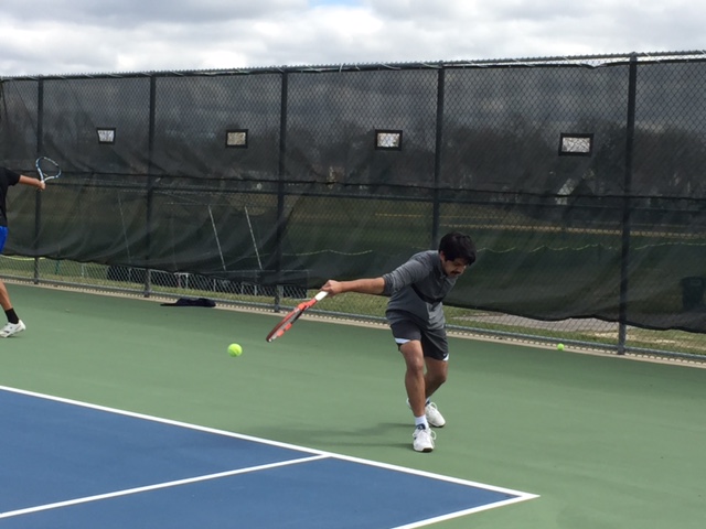 Senior Danish Mahmood backhands a ball over the net.