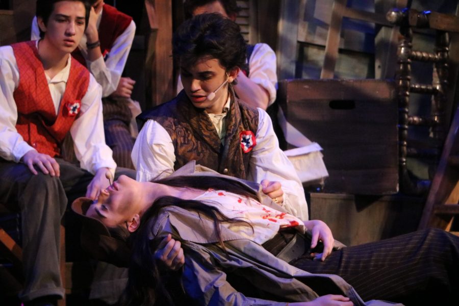 Marius (Justin Zanaska) holds Eponine (Taylor Reints) as she dies singing A Little Fall of Rain after being shot in battle. 