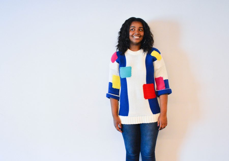 Junior Amina Smaller models a bright, geometrically printed sweater.