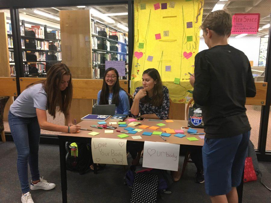 BODY LANGUAGE. HerSpace members junior Sky Li Griffiths and sophomore Isa Saavedra-Weis host members of the freshman class while they write post its to place on the Love Your Body poster.