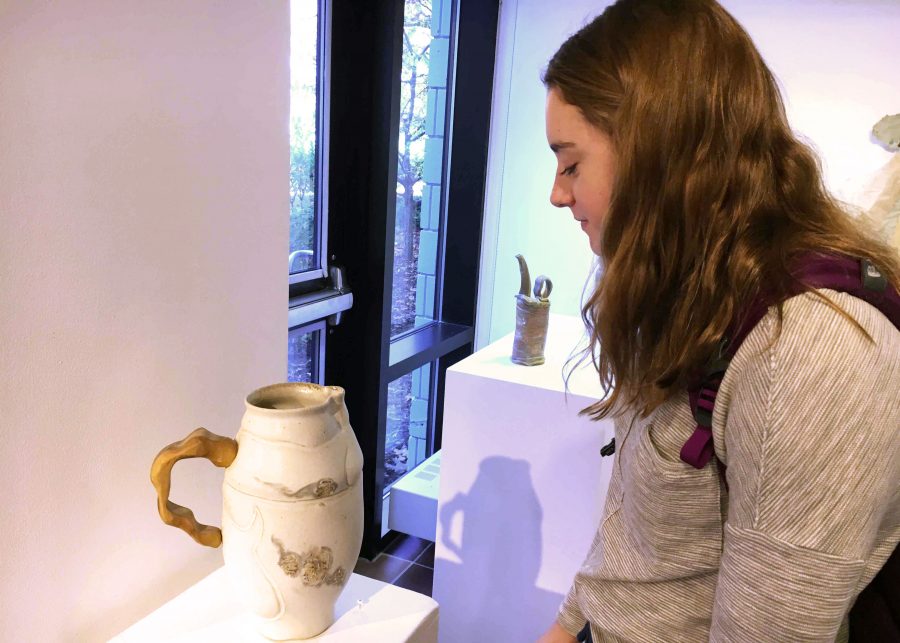 Ceramics student and sophomore Janie Brunell admires the ceramic pieces in the Harry M. Drake Gallery. "I can tell that [in this piece there are] a couple parts that were done on the wheel, but the handle had to be sculpted or carved. It's cool that they incorporated a bunch of techniques to make a piece," Brunell said while looking at a vase.