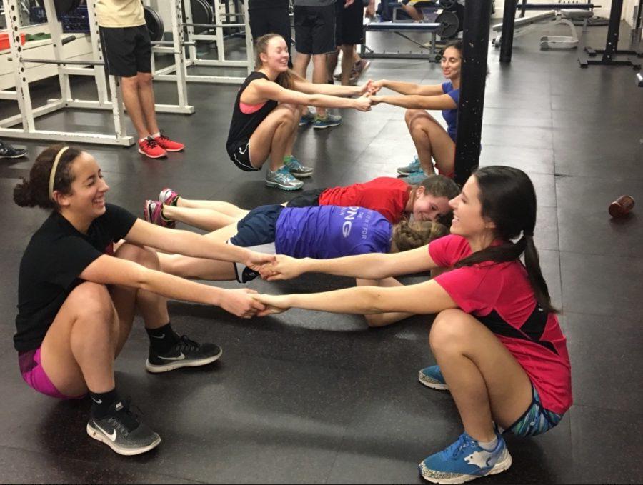 Juniors Dina Moradian and Val Hart hold hands for support while squatting during a dryland practice.“The team dynamic of the Nordic team is very inclusive and supportive. People are always cheering each other on at meets and encouraging each other at practices,” captain Nora Kempainen said. 