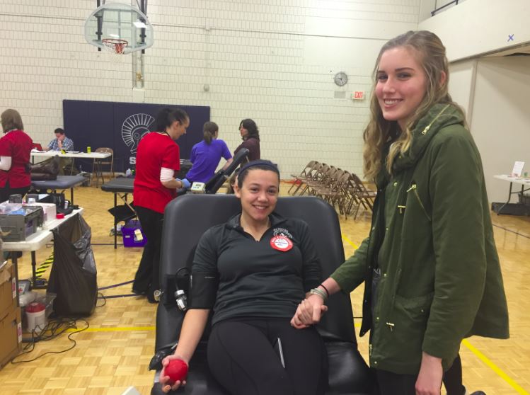 Senior Maggie Gallagher gives blood and senior Moira McCarthy supports her at the Jan. 31 Blood Drive. We organize the blood drive because people need blood and there are so many things that prevent people from donating, we want to make as many donations as possible, McCarthy said.