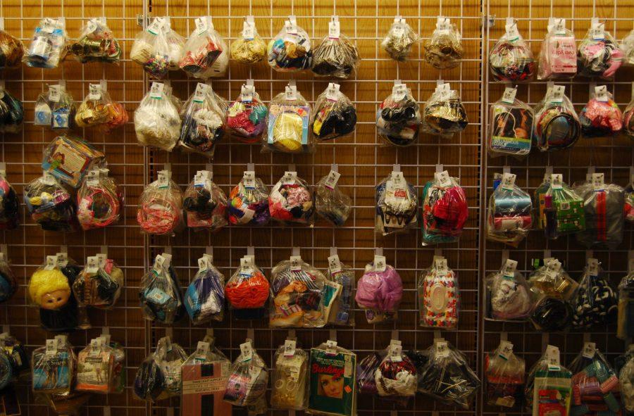 A wall in Unique Thrift Store holds plastic bags with dolls, yarn, fabric, and other items.