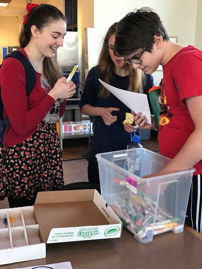 Senior Mary Grant, and juniors Flann Enneking-Norton and Jonah Harrison get markers and paper.