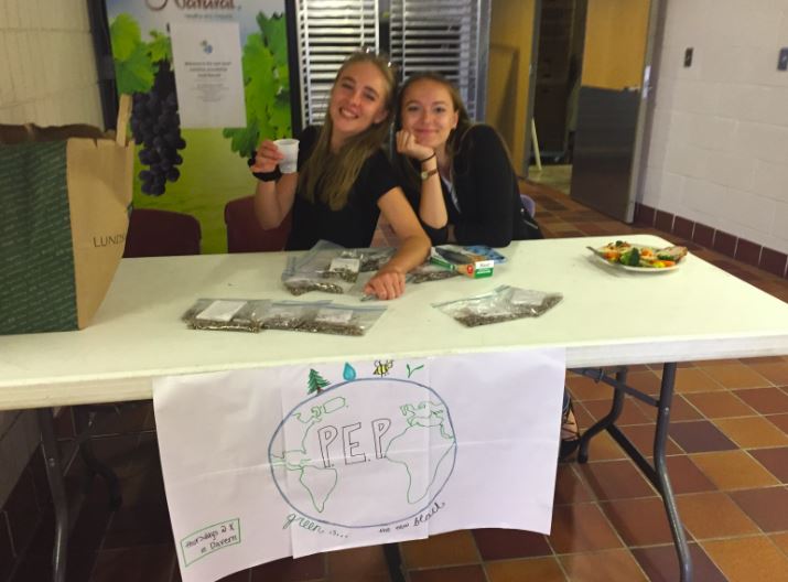 Seniors Emily Dieperink and Maya Kachian sell pollination seeds outside the lunch room. 