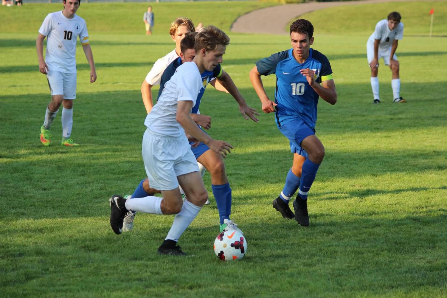 Co-captain Robin Barlett dribbles past a group of players during a game against St. Thomas Academy at Historic Lang Field. 