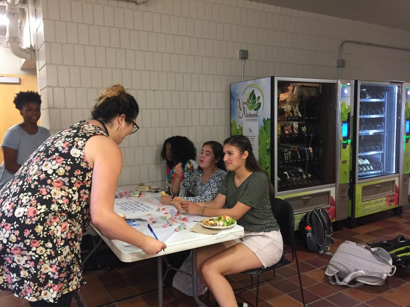 CIVICALLY ENGAGED. US English teacher Molly Olguin signs a letter addressed to President Trump defending DACA. Junior Isabel Saavedra-Weis, and seniors Eva Garcia and Amina Smaller sit behind the table while Olivia Williams Ridge encourages participation.