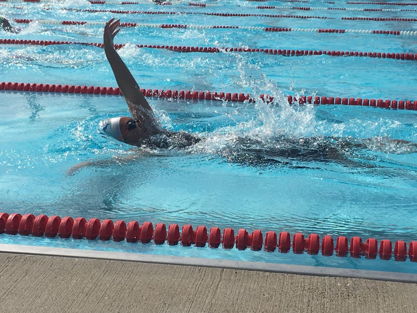 Ninth grader Jasmine White competes in the backstroke at a swim meet. White has been swimming since first grade and intends to continue competing in college. Im still too young to apply [to college], but Im already looking at a lot of different schools with great swimming programs, she said. 