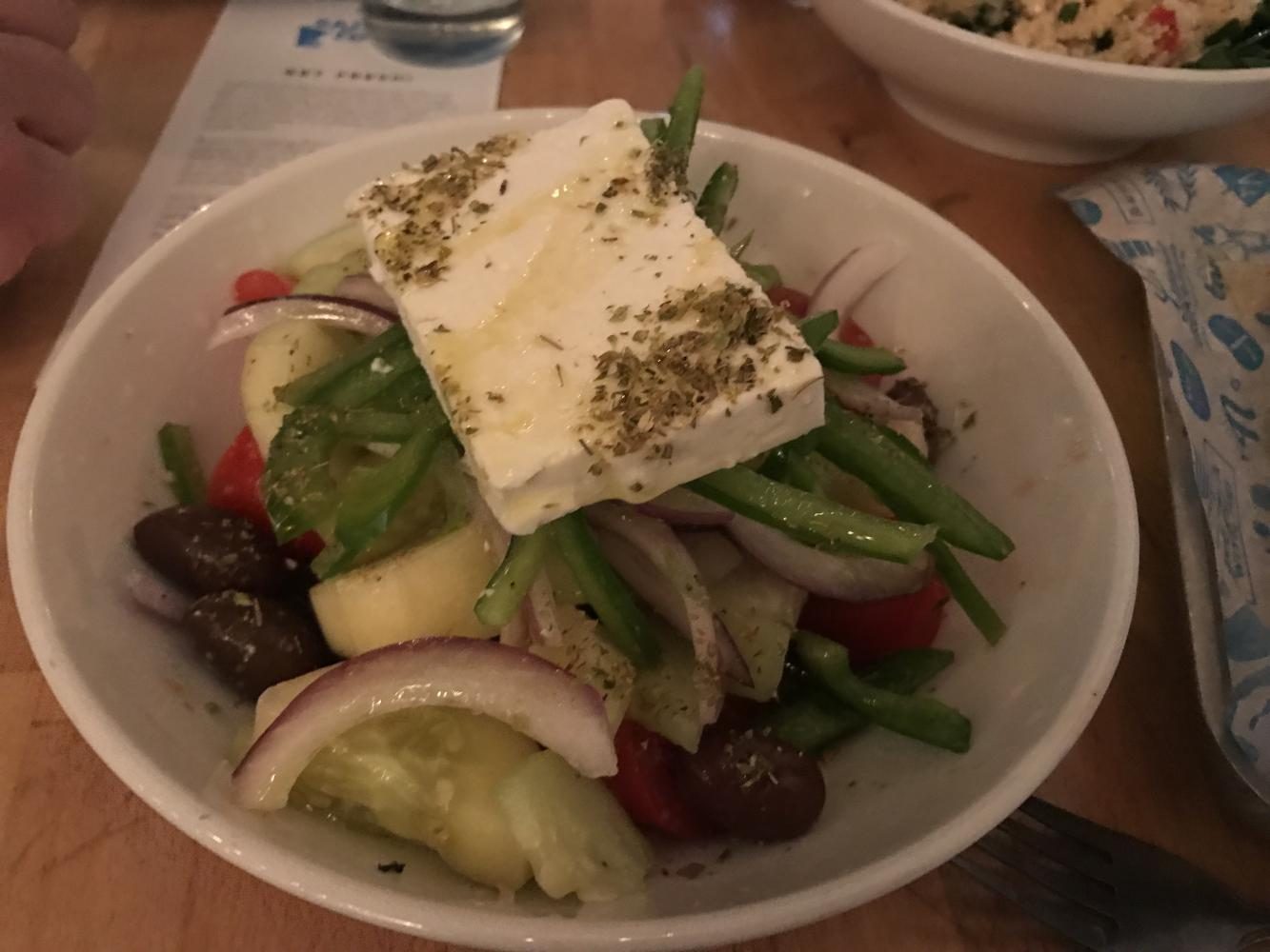 The Greek salad with feta is served on top of mix of tomatoes, olives, green beans, and cucumbers.