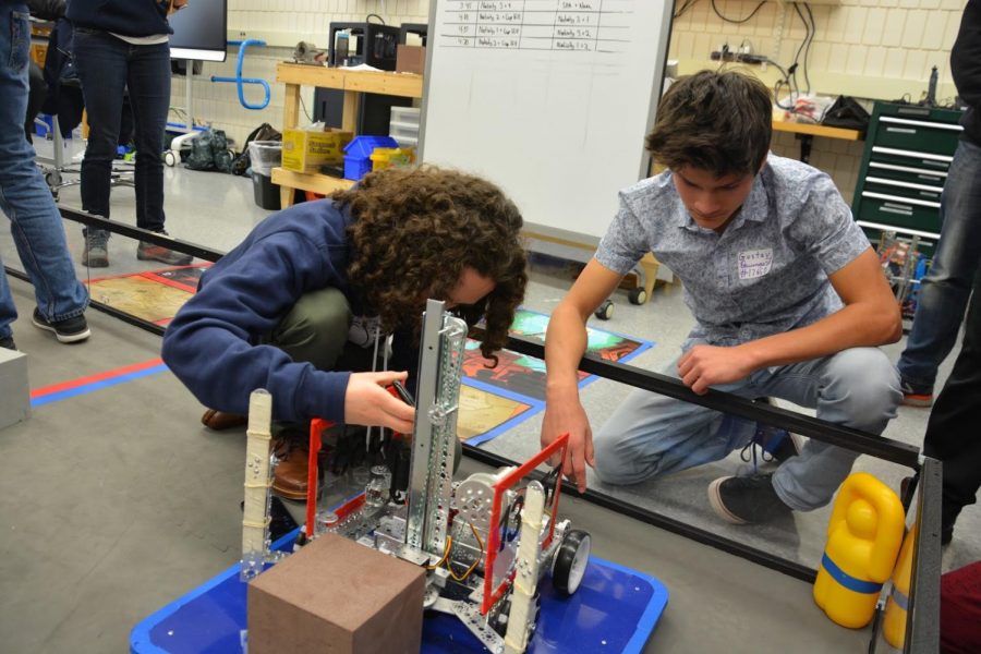 Junior Gabriel Konar-Steenberg and sophomore Gustav Baumgart examine a visitor's robot during an outreach even hosted by Spartan Robotics.