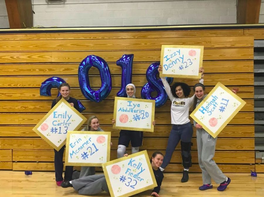 The Seniors on Girls Basketball pose with their signs after winning the game against Harding. 