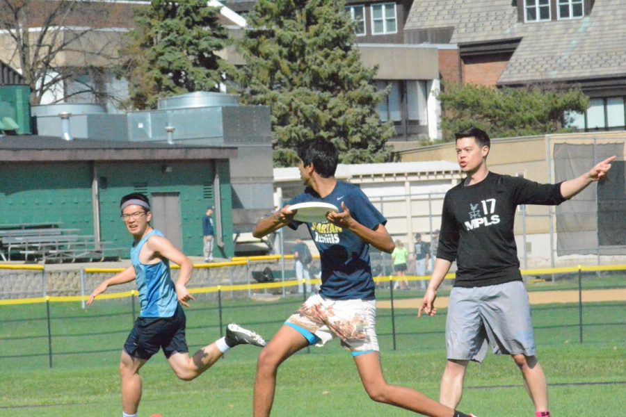 Senior Rahul Dev passes the disc to senior Larry Chen while US History teacher Ryan Oto guards on May 4 on Lang field.