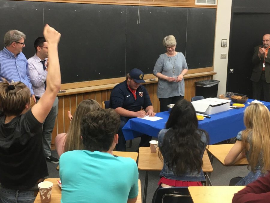 Senior Jake Adams signs his commitment form to play college sports.