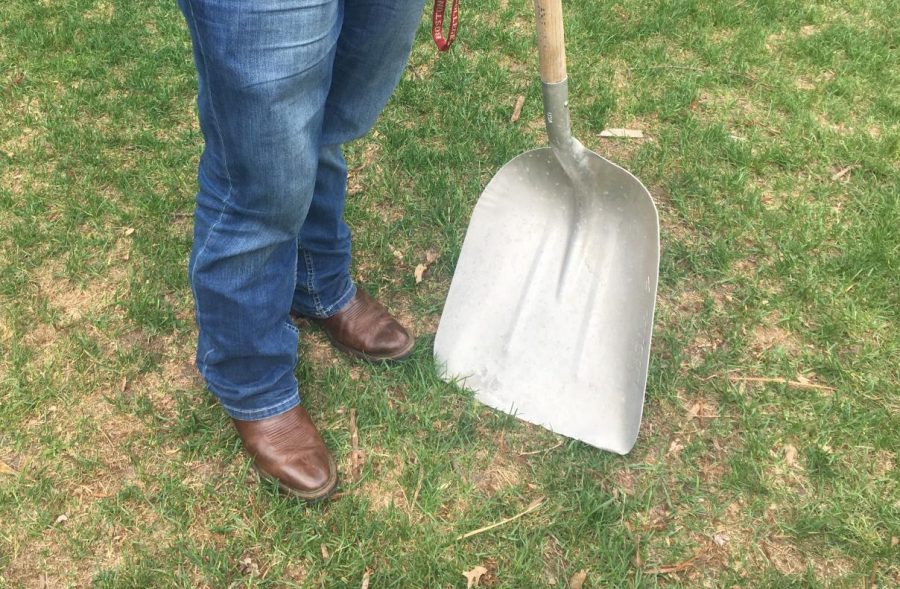 Tietel poses with a shovel and his boots; his farming essentials. 