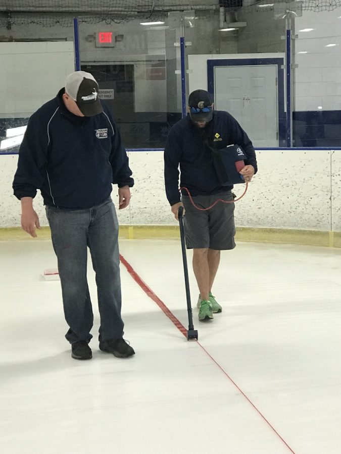 Edhlund (left) observes the painting of the ice rink.