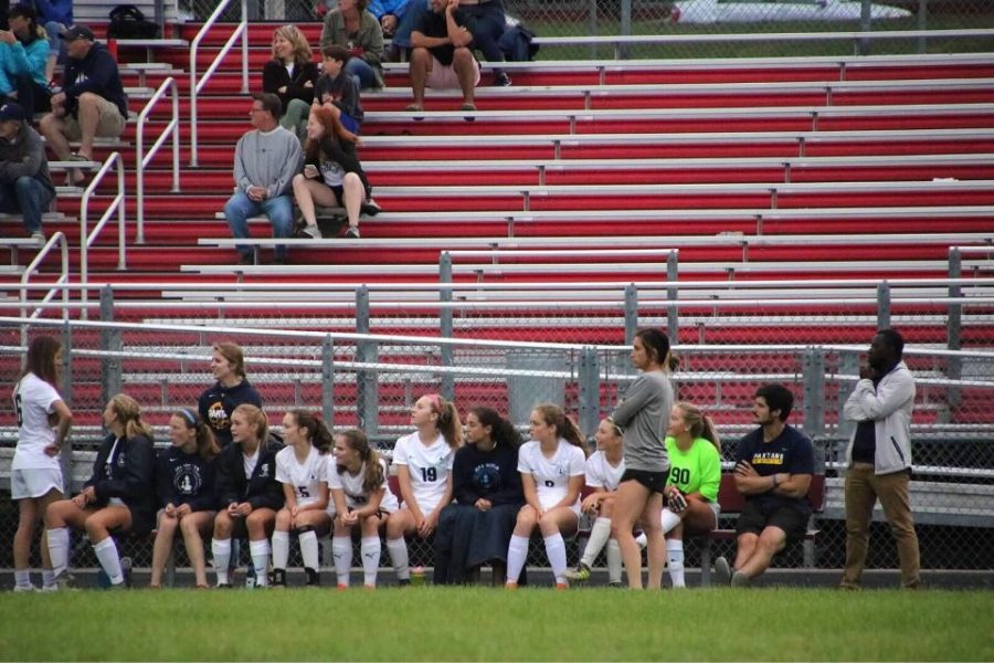 Girls varsity soccer manager Gabby Harmoning stands with her team. Her role as a manager is [...] just supporting the team as a whole. The entire bench is captivated with the game. This was an early season game when the team was still getting into the flow of play.