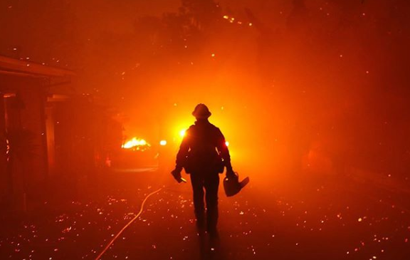 A firefighter walks through the blaze of the Woolsey fire in Malibu, California. 