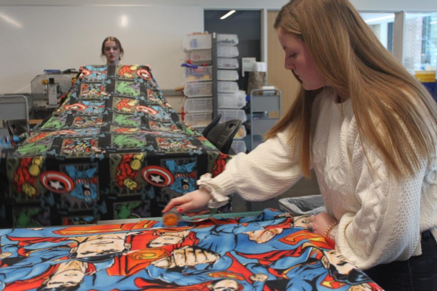 CAS president and senior Ellie Nowakowski cuts pieces of fleece blanket with help of CAS members.