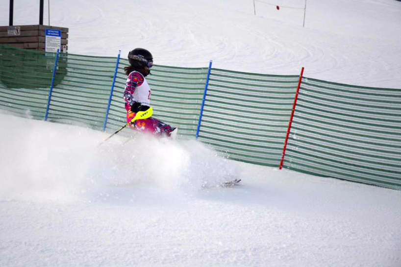 Senior Sammy Ries sprays snow as she comes to a stop at the bottom of the hill.