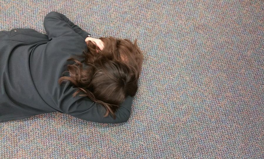 Senior Eliza Reedy naps on the floor of the Lower Library during the last Monday of her high school career. 