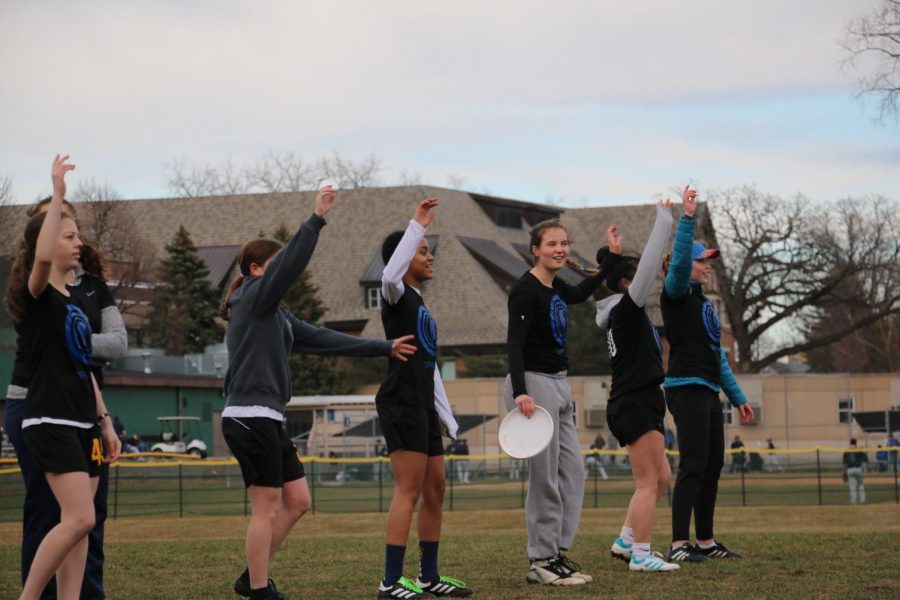 The Girls Ultimate Team raises their hands before pulling the frisbee for the play.