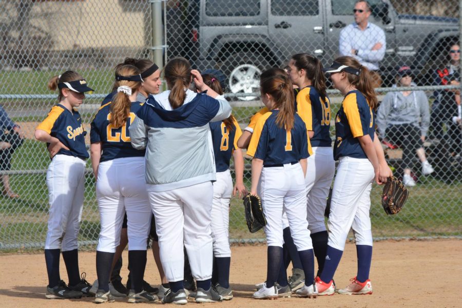 The softball team huddles before their game begins.