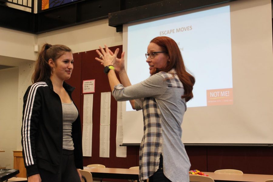 Senior Isabel Saavedra-Weis helps with an example during the self defense class. 